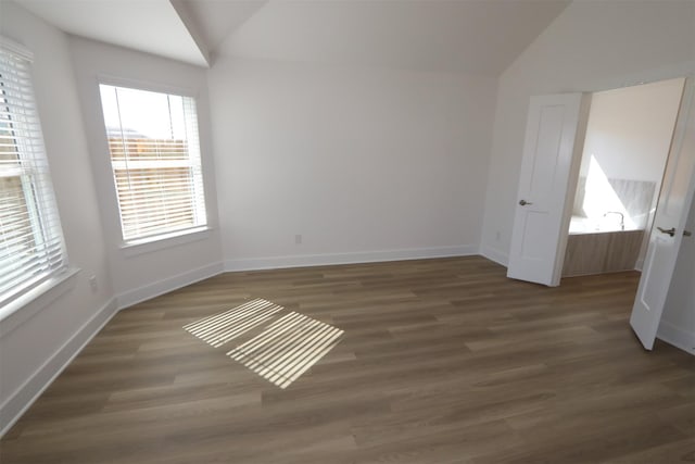 unfurnished room with wood finished floors, baseboards, and vaulted ceiling