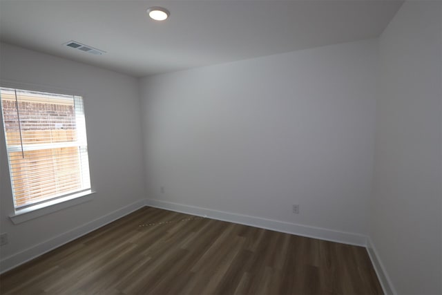 empty room featuring baseboards, visible vents, and dark wood-style flooring