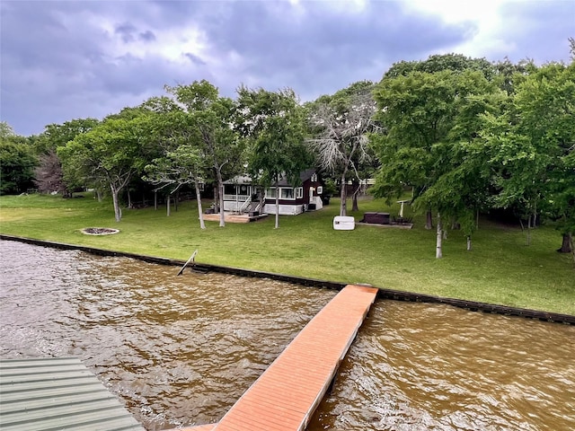 view of dock with a water view, a yard, and an outdoor fire pit