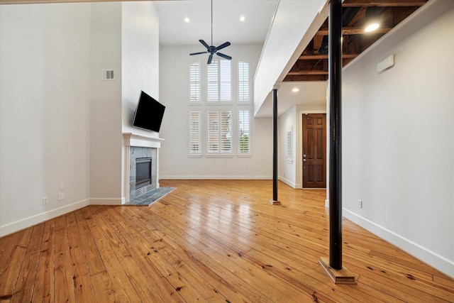 unfurnished living room featuring a high end fireplace, ceiling fan, and light hardwood / wood-style floors