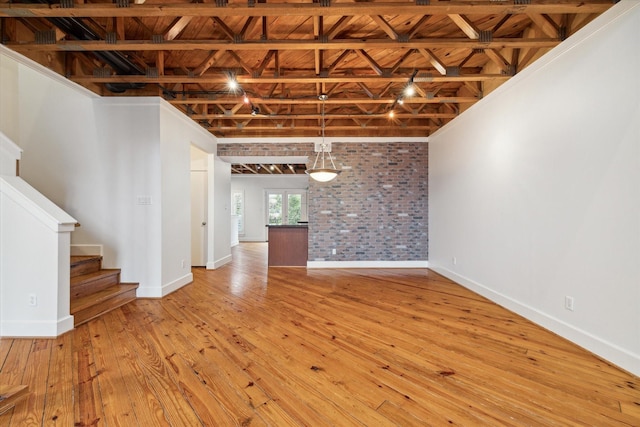 unfurnished living room featuring light hardwood / wood-style floors and brick wall