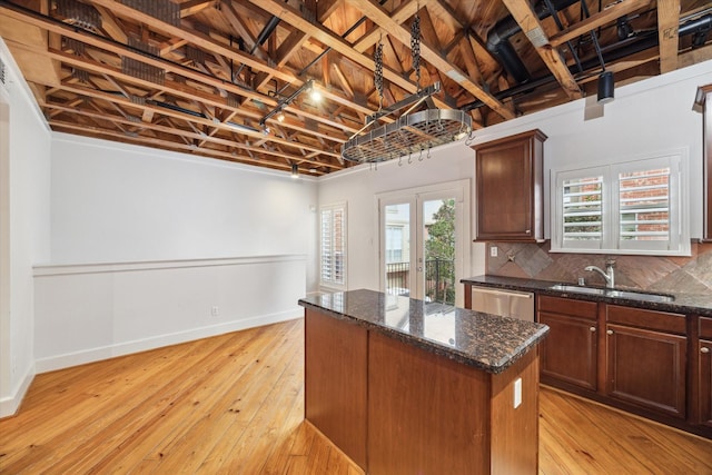 kitchen with stainless steel dishwasher, decorative backsplash, a kitchen island, light wood-type flooring, and sink