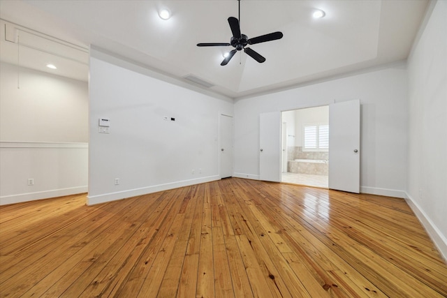 unfurnished room with vaulted ceiling, ceiling fan, light hardwood / wood-style floors, and a tray ceiling