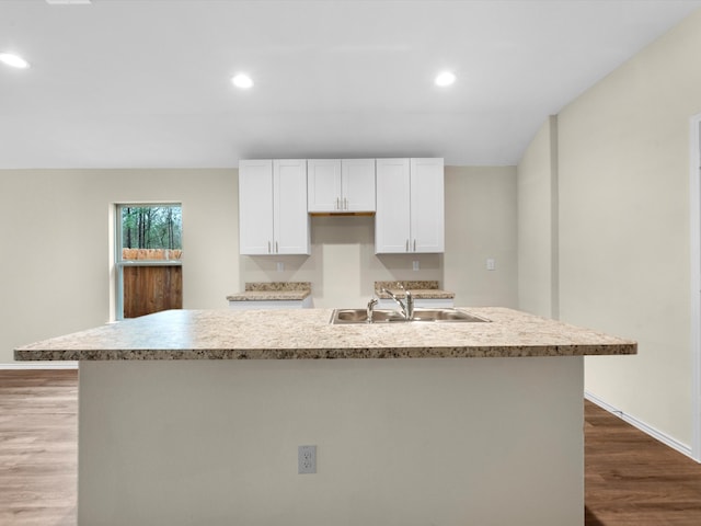 kitchen featuring light wood-type flooring, sink, an island with sink, and white cabinets