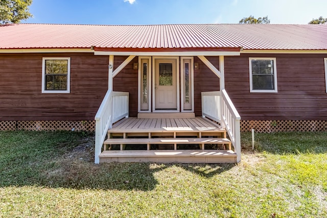 view of exterior entry featuring a lawn