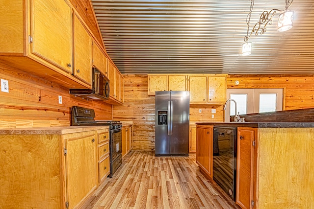 kitchen featuring black appliances, pendant lighting, beverage cooler, wooden walls, and light wood-type flooring