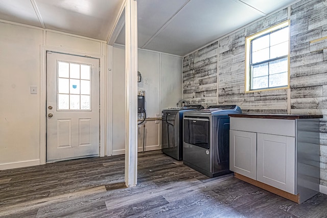 clothes washing area with a healthy amount of sunlight, dark hardwood / wood-style flooring, washing machine and dryer, and cabinets