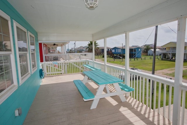 wooden terrace featuring covered porch and a lawn