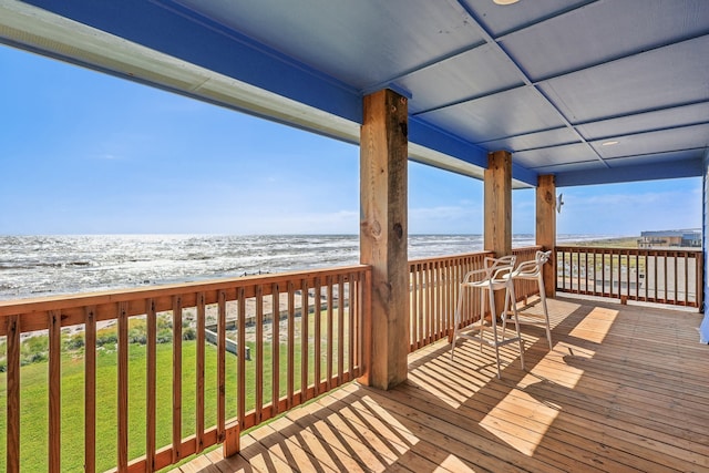 wooden deck with a beach view, a water view, and a yard