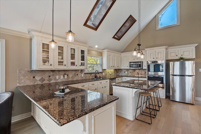 kitchen featuring a breakfast bar, pendant lighting, stainless steel appliances, and a skylight