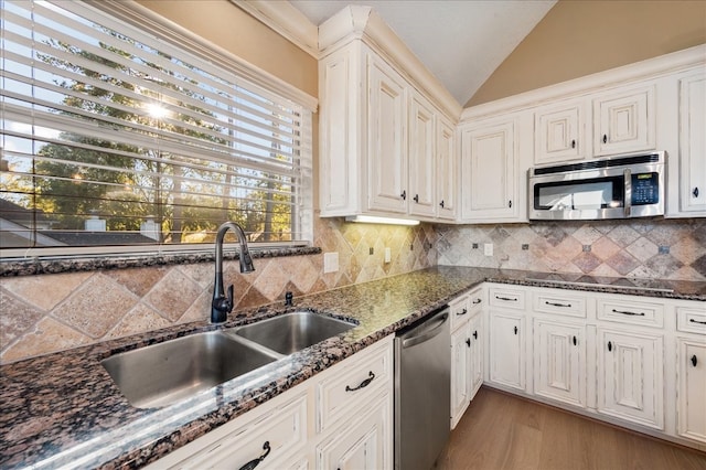 kitchen featuring sink, white cabinetry, stainless steel appliances, and vaulted ceiling