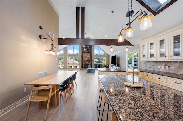 kitchen featuring hardwood / wood-style floors, dark stone counters, hanging light fixtures, and a breakfast bar area