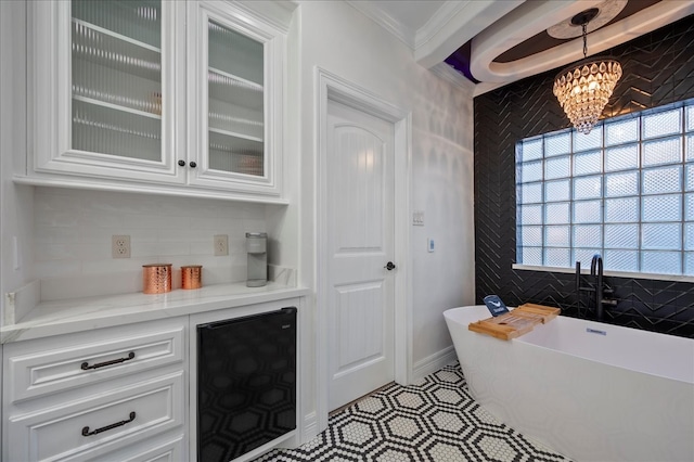 interior space with beverage cooler, crown molding, pendant lighting, white cabinets, and a chandelier