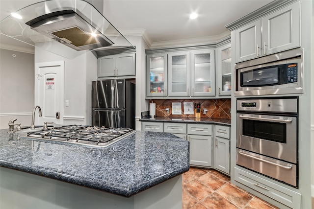 kitchen with stainless steel appliances, dark stone counters, range hood, and ornamental molding