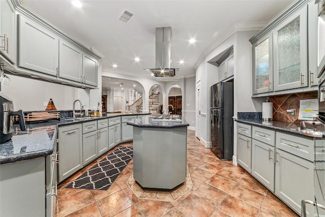 kitchen featuring dark stone counters, black fridge, sink, and a center island