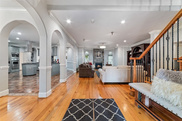 living room with ornamental molding, light hardwood / wood-style flooring, and a tile fireplace