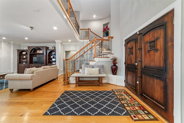 foyer entrance featuring hardwood / wood-style floors, ornate columns, and crown molding