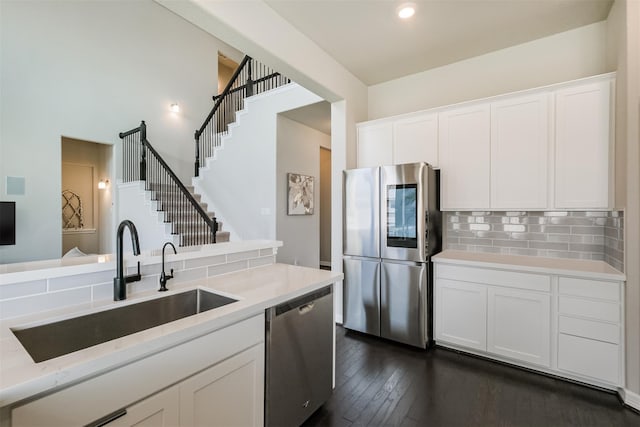 kitchen featuring white cabinetry, sink, appliances with stainless steel finishes, tasteful backsplash, and dark wood-type flooring