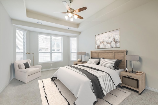 bedroom with ceiling fan, light carpet, and a raised ceiling