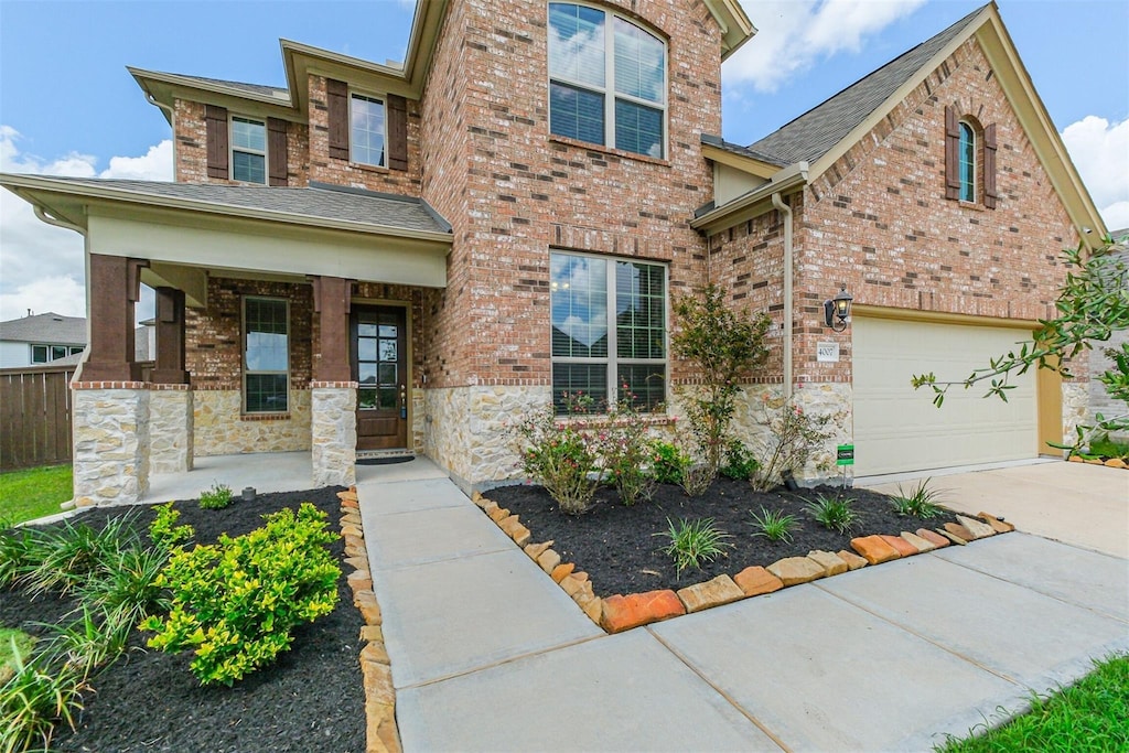 4007 Martin Ridge Dr, Manvel, TX 77578 - view of front facade featuring a porch, an attached garage, brick siding, driveway, and stone siding