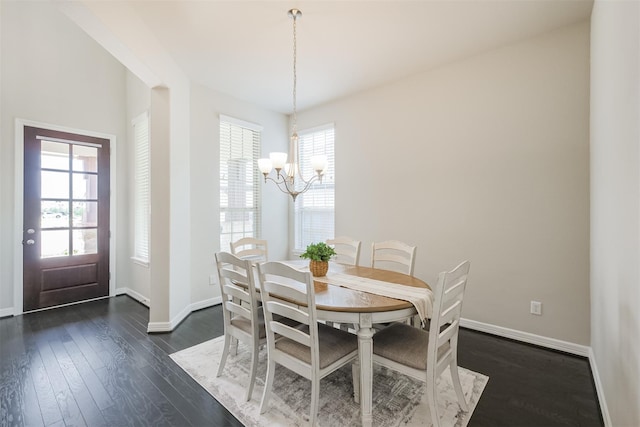 dining space with dark hardwood / wood-style floors and an inviting chandelier