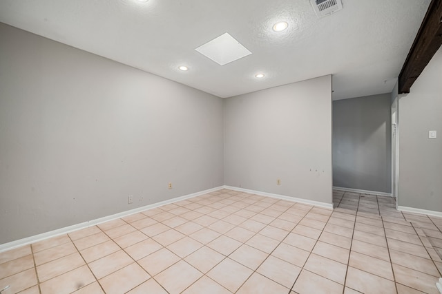 tiled empty room with a textured ceiling