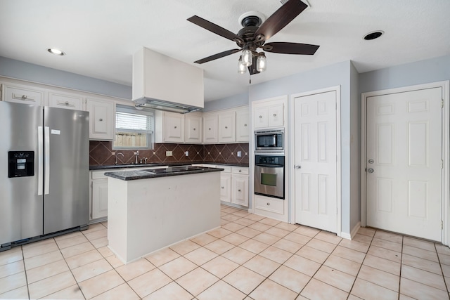 kitchen featuring appliances with stainless steel finishes, tasteful backsplash, ceiling fan, a center island, and white cabinetry