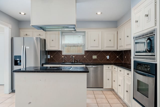 kitchen featuring appliances with stainless steel finishes, sink, light tile patterned floors, white cabinets, and a center island