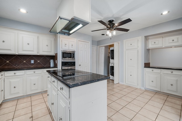 kitchen featuring stacked washer and clothes dryer, appliances with stainless steel finishes, a kitchen island, white cabinetry, and extractor fan