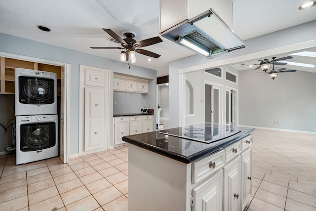 kitchen with a center island, range hood, stacked washer and dryer, electric cooktop, and light tile patterned flooring