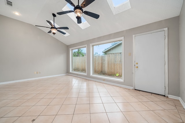 empty room featuring light tile patterned floors, ceiling fan, and vaulted ceiling with skylight