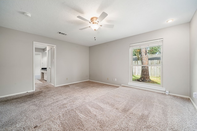 spare room featuring light carpet, ceiling fan, and a textured ceiling