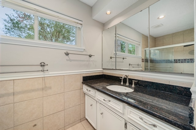 bathroom with vanity, tile patterned floors, tile walls, and a shower with shower door