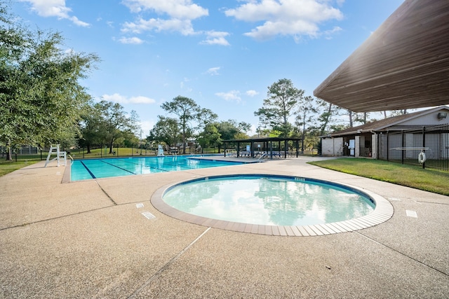 view of pool with a community hot tub, a patio area, and a lawn