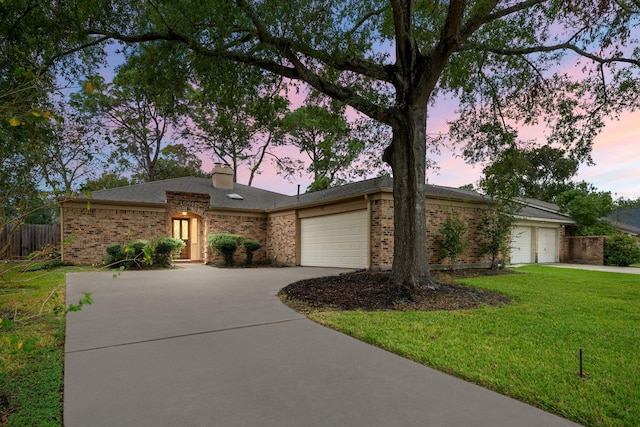 ranch-style home featuring a lawn and a garage