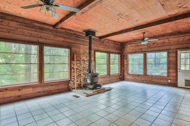 unfurnished living room featuring a wood stove, light tile patterned floors, ceiling fan, and wooden ceiling