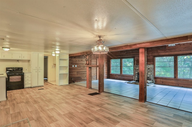 interior space featuring light hardwood / wood-style floors, wood walls, a textured ceiling, and ceiling fan