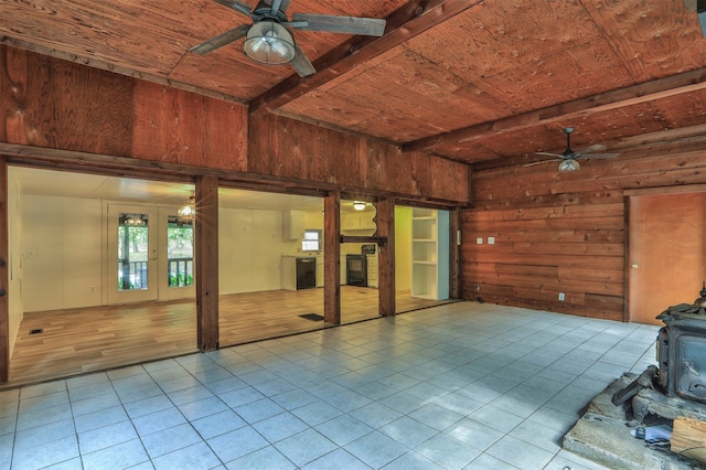 interior space featuring wood ceiling, a wood stove, wooden walls, light tile patterned flooring, and beam ceiling