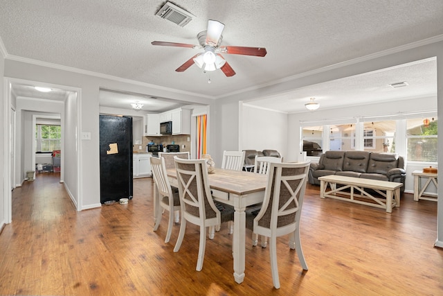 dining room featuring light hardwood / wood-style floors, a textured ceiling, crown molding, and ceiling fan