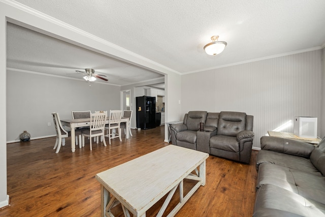 living room with dark wood-type flooring, ceiling fan, a textured ceiling, and ornamental molding