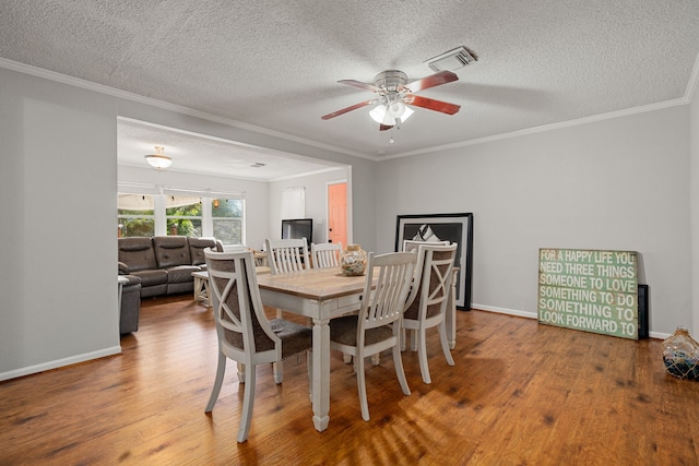 dining space featuring a textured ceiling, ornamental molding, hardwood / wood-style flooring, and ceiling fan