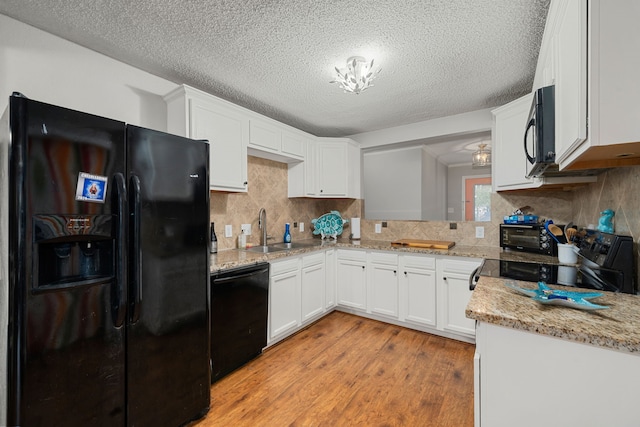 kitchen with white cabinetry, light hardwood / wood-style flooring, black appliances, and light stone counters