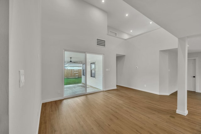 unfurnished living room with a high ceiling, light hardwood / wood-style flooring, and ceiling fan