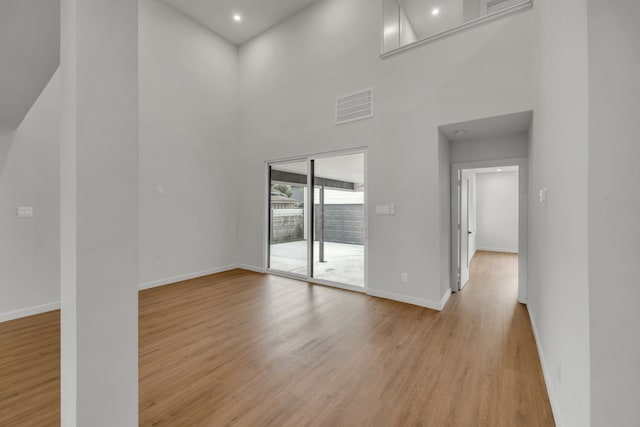 empty room with a high ceiling and light hardwood / wood-style floors