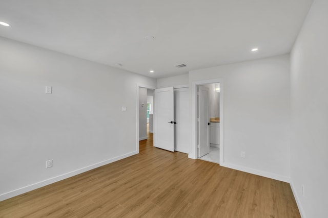 unfurnished bedroom featuring light hardwood / wood-style floors and ensuite bath