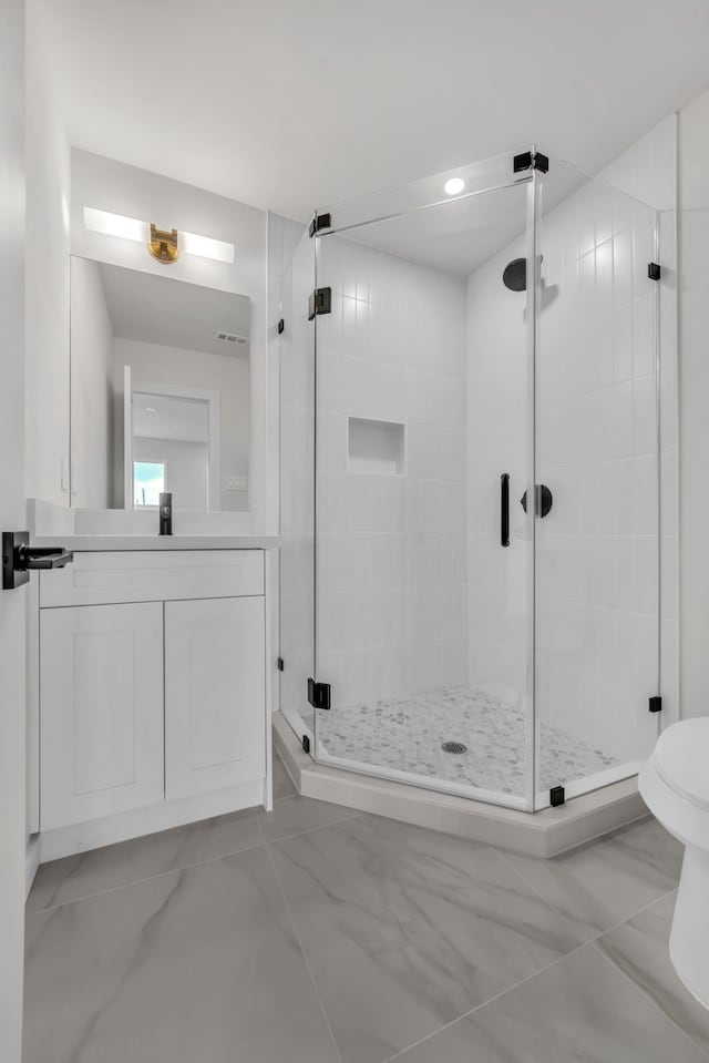 bathroom with vanity, toilet, and a shower with shower door