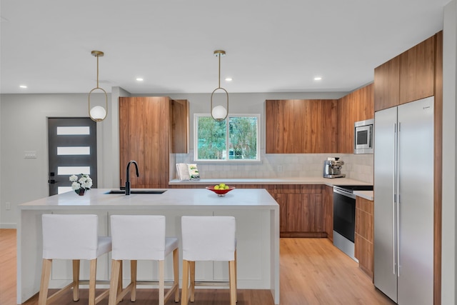 kitchen featuring built in appliances, light hardwood / wood-style flooring, hanging light fixtures, and sink