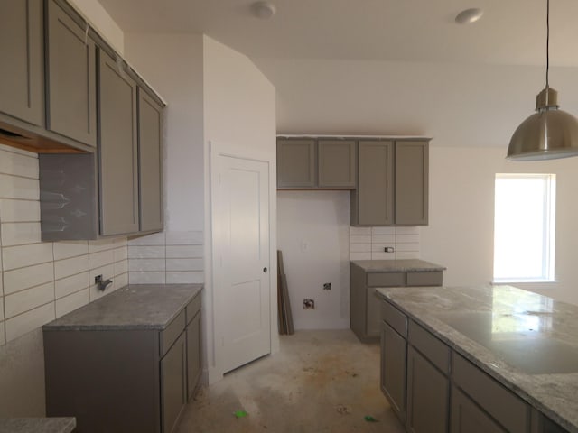 kitchen with light stone counters, hanging light fixtures, decorative backsplash, and gray cabinets