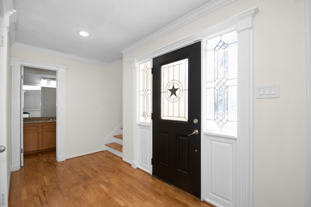 entrance foyer with ornamental molding and light hardwood / wood-style floors