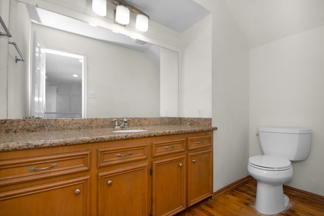 bathroom with hardwood / wood-style floors, vanity, toilet, and lofted ceiling